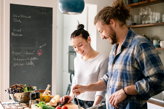 Young couple preparing food together, tasting spaghetti