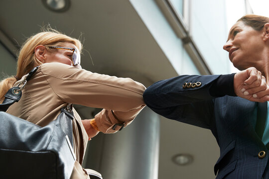 Smiling colleagues greeting with elbow bump while standing in city