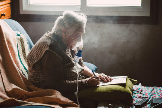 Senior woman using inhaler at home