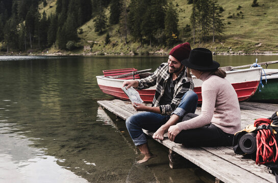 Austria, Tyrol, Alps, couple with map sitting on jetty at mountain lake