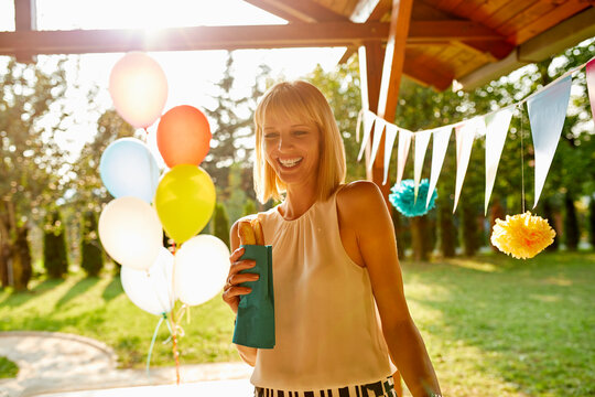 Happy woman eating a hot dog on a garden party