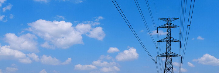 Obraz premium Electric pylon reaching towards the bright blue sky. The image captures the structure against a backdrop of clouds, a testament to modern engineering 