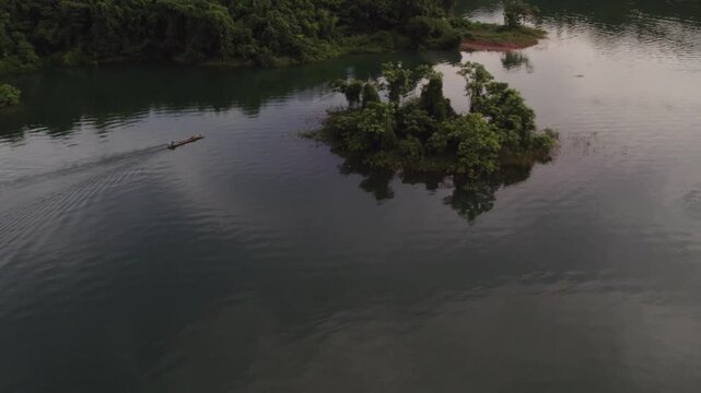 Fisherman driving a small fishing boat around a small siland in the Nam Ngam Lake during the rainy season.