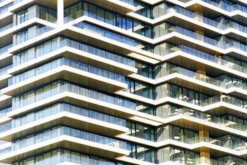 Geometric pattern of glass balconies and white concrete slabs on modern residential tower....