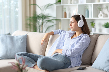 Woman wearing headphone listening audio and looking away at home