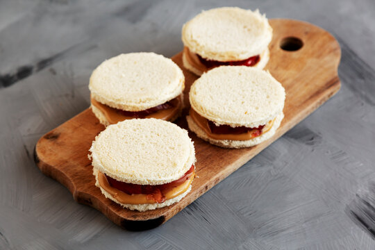 Homemade Round Crustless Peanut Butter and Jelly Sandwich on a Wooden Board, side view.