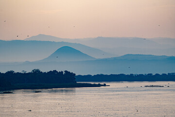 Naklejka premium Serene misty mountains and river at sunset
