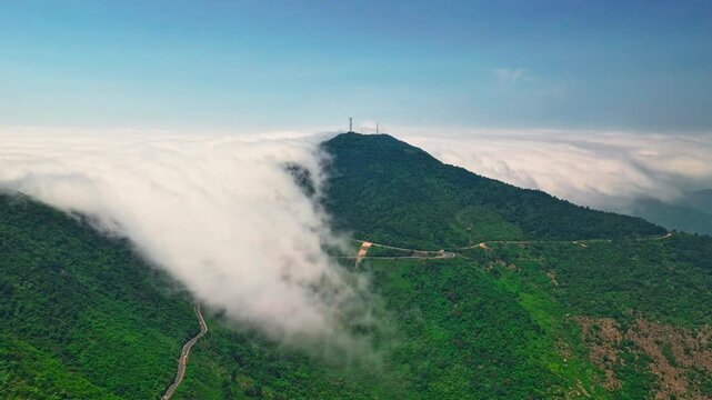 Aerial timelapse of clouds flowing over green mountain ridge