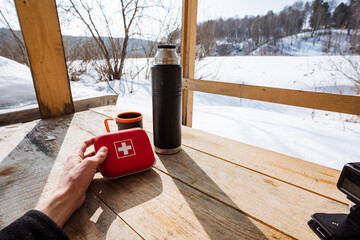 Preparing Gear Before Outdoor Trek. Individual Examines First Aid Items On Porch. Hiker Carefully Inspects First Aid Supplies On Front Porch With Scenic Snowy Valley Background © Aleksey