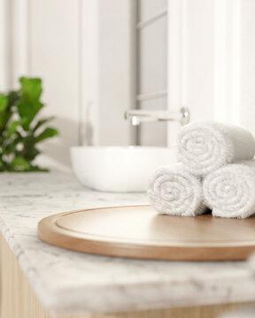 White towels on round wooden tray at marble sink counter aside houseplant in bright modern bathroom