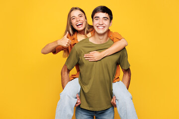 Fototapeta premium Young happy couple friends family man woman wear shirt casual clothes together giving piggyback ride to joyful, sit on back isolated on pastel plain light yellow background studio. Lifestyle concept.