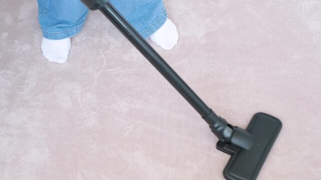 A woman vacuuming carpet with white cordless vacuum cleaner, top view.