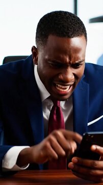 Angry African American businessman looking at smartphone with frustrated expression in office