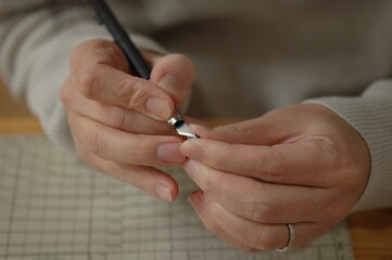 プラモデルのパーツをカッターを使って削る様子の手元