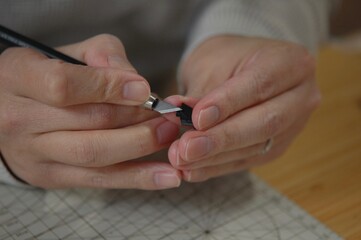 プラモデルのパーツをカッターを使って削る様子の手元