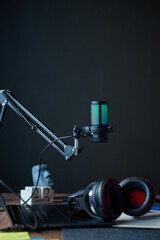 Fototapeta premium Home creator desk with RGB microphone on boom arm headphones and laptop for recording. Concept of podcast streaming broadcast and digital content creation