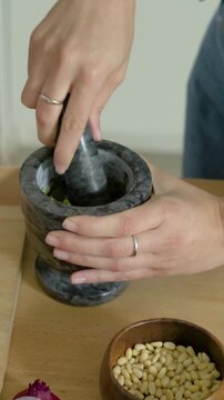 Vertical video: Slicing onion, cook in plaid mashing herbs, onion with mortar and pestle for pesto