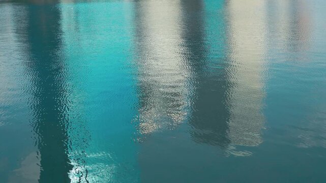 Reflection of Modern Office Buildings on Rippled Blue Water Surface