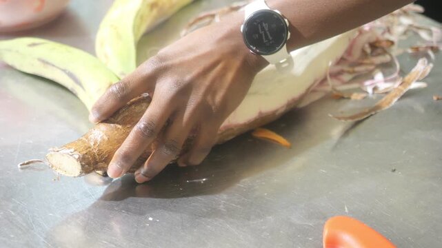 African chef preparing cassava root for traditional cuisine in a professional kitchen