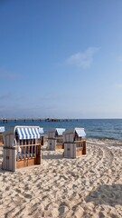 Fototapeta premium Strandkörbe on Rugen sandy beach with pier and calm Baltic Sea horizon