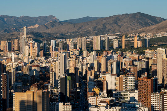 Rooftops spread beneath a mountain in a wide Benidorm Spain city panorama with an urban skyline and modern architecture in crisp clear daylight