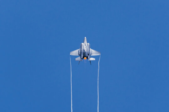 Aerial view of a F35 fighter jet soaring through the expansive blue sky, leaving vapor trails behind during an airshow, Singapore Air Show 2026, Singapore.