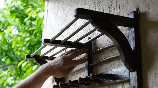 Hand hanging a baseball cap on a vintage wooden wall rack