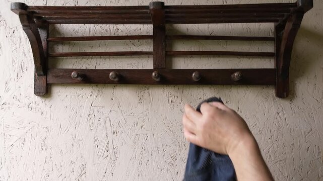 Man hanging a baseball cap on a vintage wooden wall rack