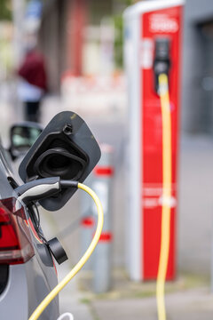 Sustainable mobility scene in Hamburg Germany showing electric vehicle charging with plug at station highlighting energy technology and urban transport