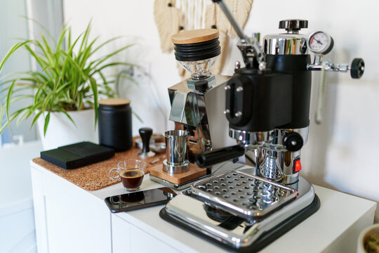 Home barista station with manual lever espresso machine, single dose grinder, and a smartphone on the counter