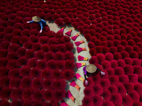 Aerial view of vibrant red incense sticks laid out to dry, creating a striking contrast with the workers, Kolkata, West Bengal, India.