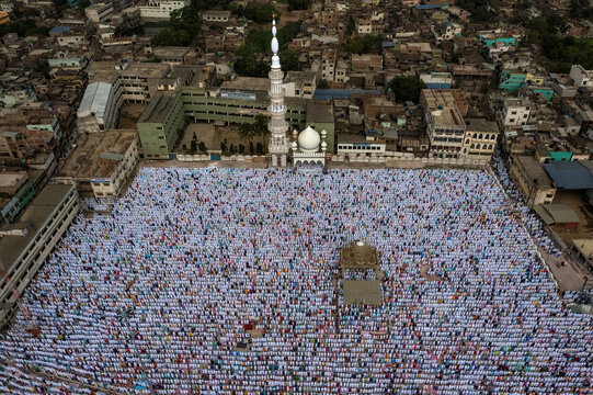 Aerial view of a vast gathering of people in white, praying at the Nakhoda Masjid, framed by dense urban textures, Kolkata, West Bengal, India.