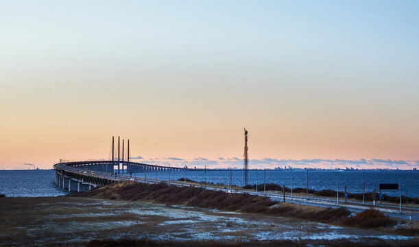 Sunset view from Lernacken of the &Ouml;resund Bridge curving over calm sea conveys infrastructure concept. Distant city of Copenhagen and coastal road in winter landscape between Sweden and Denmark