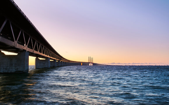 Sunset over &Ouml;resund Bridge connecting Malmo, Sweden to Copenhagen, Denmark stretching into the distance above rippling sea with a warm sky. Cross border, modern Scandinavian infrastructure concept