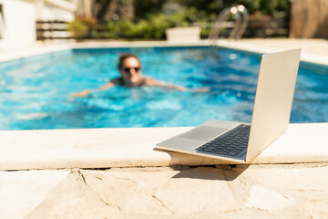 Fototapeta premium A woman trains in a swimming pool with a laptop