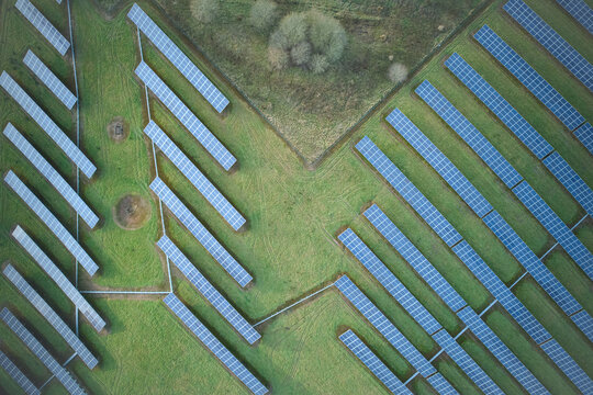 Aerial view of solar panels arrayed in neat rows across a lush green field near Old Road, creating a geometric pattern against the natural landscape, Stoke-on-Trent, England, United Kingdom.