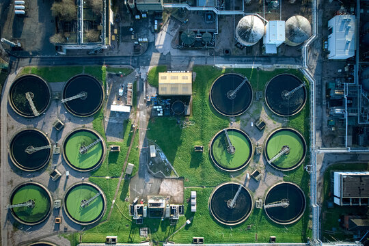 Aerial view of circular tanks, some with vibrant green contents, contrasting against the industrial landscape of concrete and metal structures, Stoke-on-Trent, England, United Kingdom.