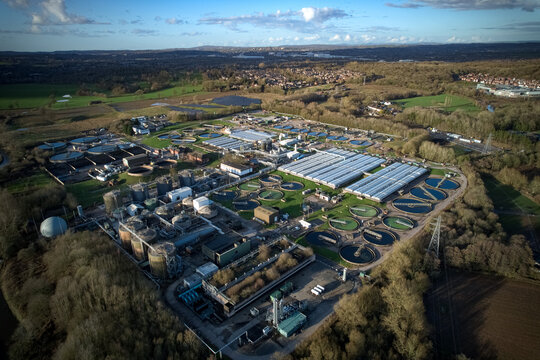 Aerial view of an industrial complex with tanks and buildings, nestled among green fields and trees, creating a stark contrast between nature and industry, Stoke-on-Trent, England, United Kingdom.