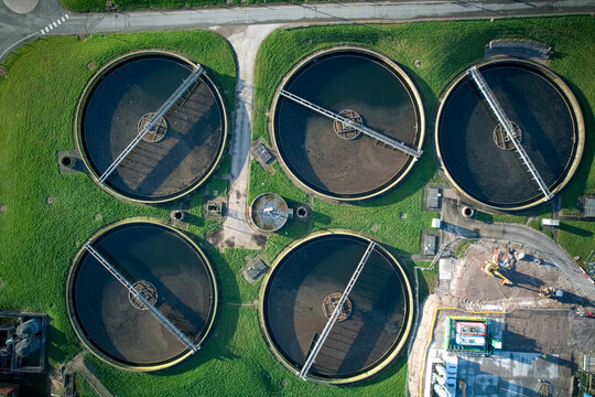Aerial view of circular water treatment tanks surrounded by green grass and concrete structures, Stoke-on-Trent, England, United Kingdom.