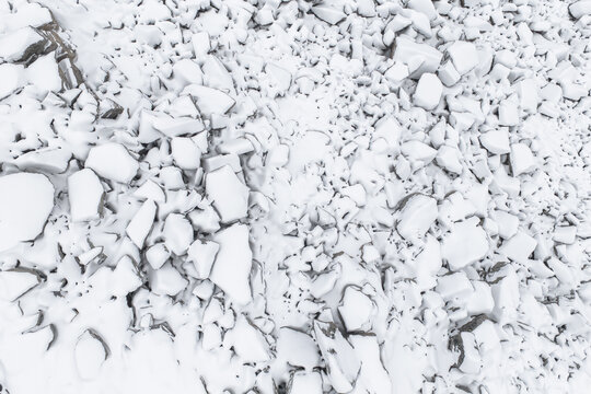 Aerial view of a landscape dominated by the stark white of snow-covered rocks and boulders, their jagged edges softened by the fresh snowfall, Senjahopen, Troms, Norway.