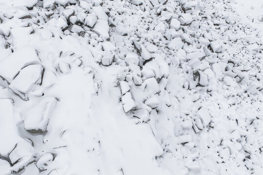 Aerial view of a landscape blanketed in pristine white snow, the rugged rocks and crags softened by the heavy snowfall, Senjahopen, Troms, Norway.