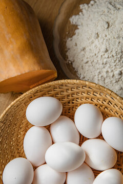 White eggs and flour in rustic home baking preparation on wooden table