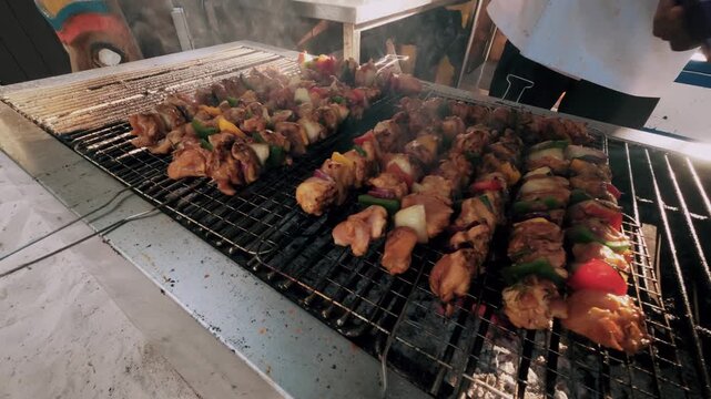 Street food vendor grilling meat skewers on barbecue grill