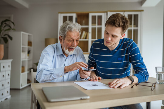Young man helping senior scanning document with smart phone