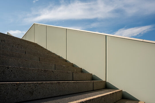 Concrete stair geometry beside an urban wall under clear sky creating a minimal abstract architecture scene and a spacious background for text