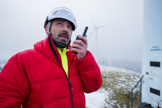 Worker in red jacket communicating via radio at wind energy facility