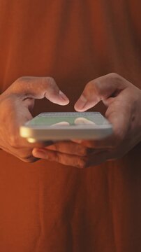 Macro close-up of a man&rsquo;s hands chatting and typing on a smartphone, using the WhatsApp messaging app on social media.