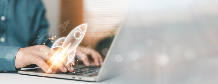 Business professional typing on laptop with glowing rocket startup icon launching upward. Concept of startup business growth, innovation strategy, digital entrepreneurship, technology success and new