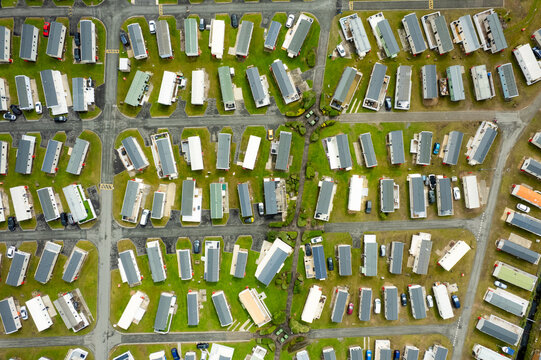 Aerial view of neatly arranged caravans casting shadows on green patches, creating a geometric tapestry of summer homes, Porthmadog, Wales, United Kingdom.