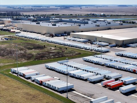 Aerial view of a vast industrial complex contrasted against open fields, with rows of trailers parked neatly, Greensburg, Indiana, United States.